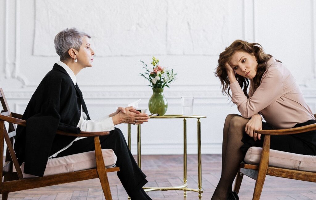 Conflict between older woman and younger woman sitting on brown wooden chair