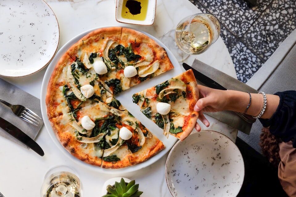 flat bread pizza with cheese, spinach, and tomato toppings, glass of white wine and dipping oil