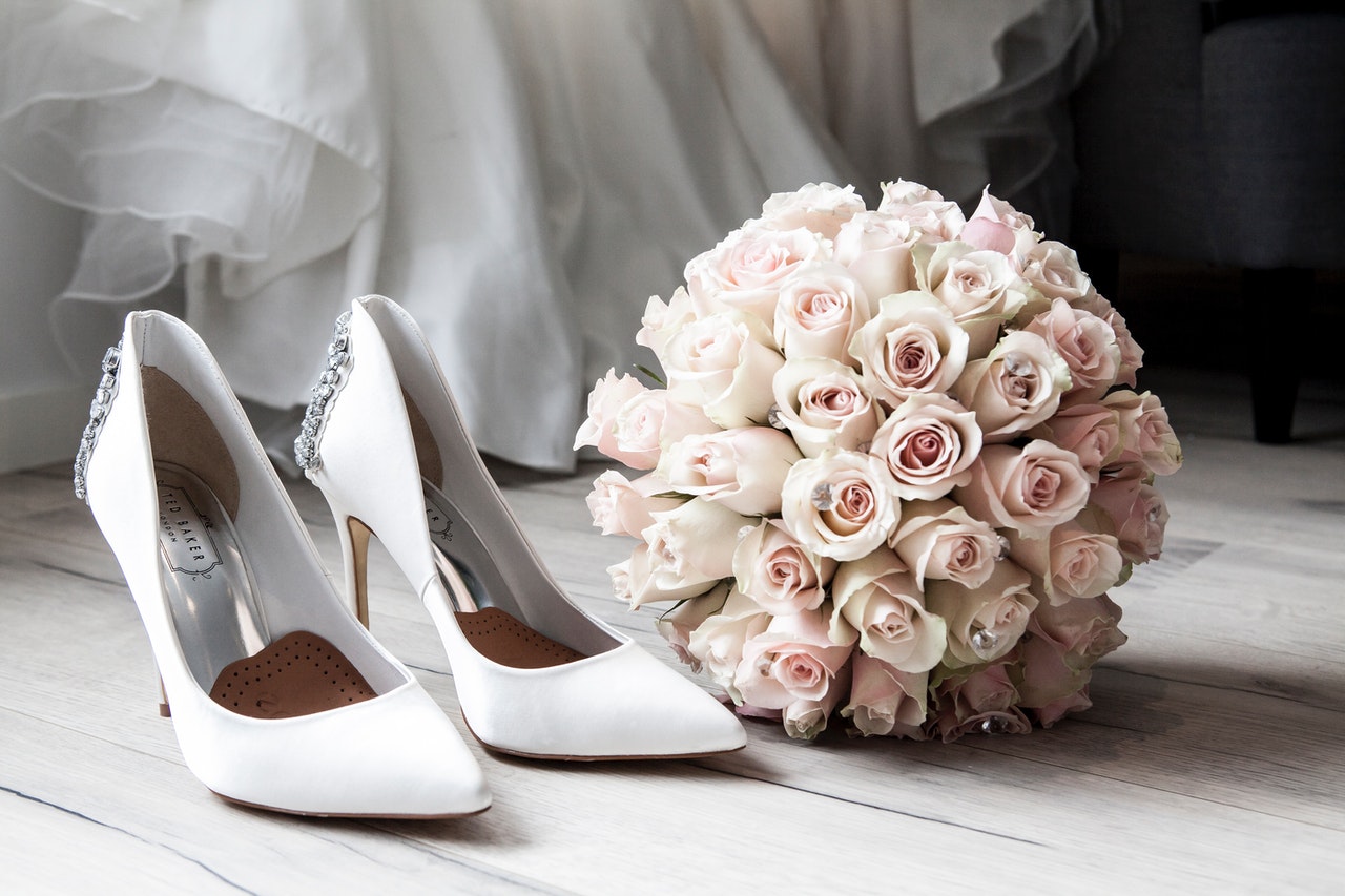 white pointed-toe high heels, pink pastel wedding flower bouquet, hem of white wedding dress