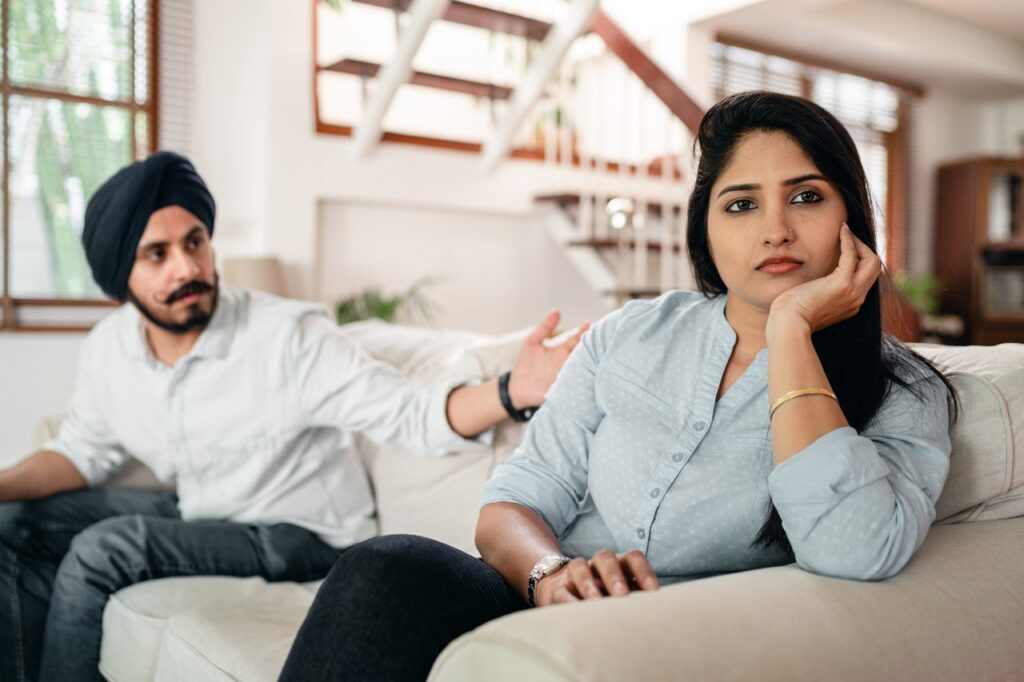 Young Indian couple sitting on couch having a conflict at home