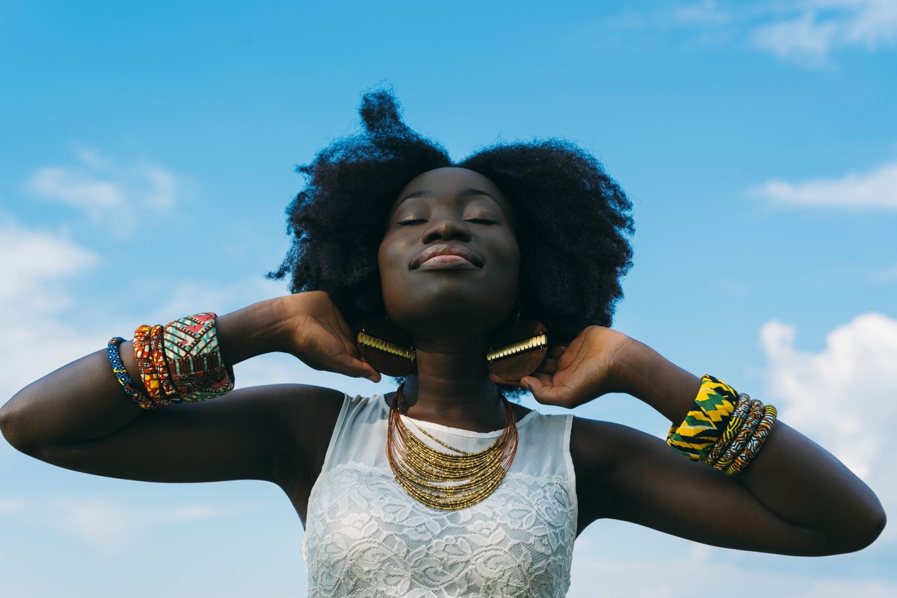 Black woman with large afro wearing white sleeveless lace shirt peaceful about racism