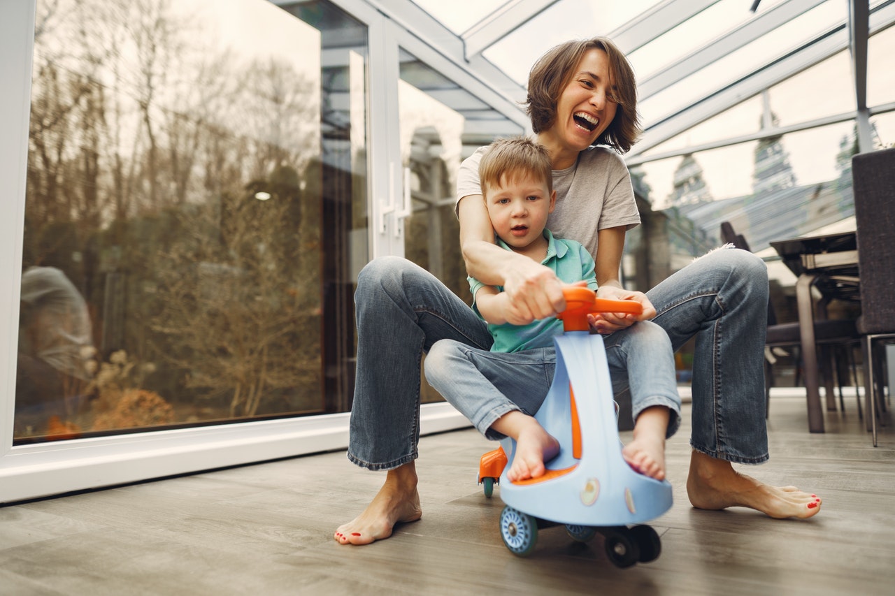 Mom parenting son while riding child's twist bike