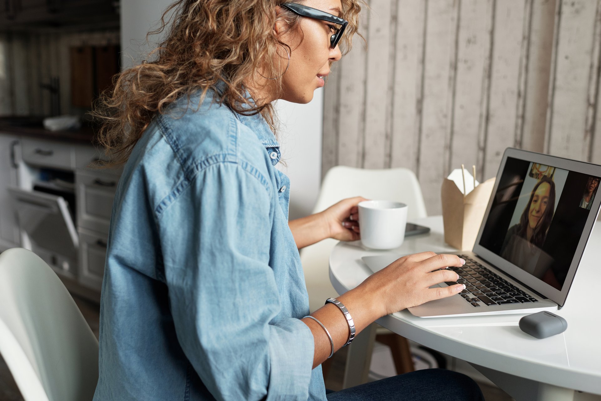 Woman in blue denim jacket using macbook pro to video chat, social distancing.