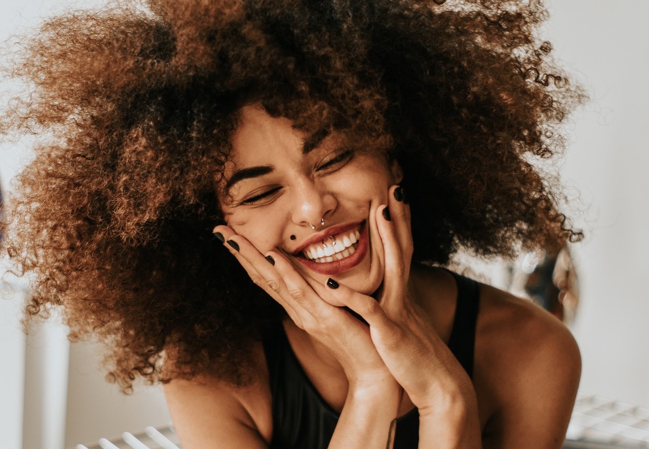 Light skinned black woman sitting in chair smiling, not experiencing burnout.