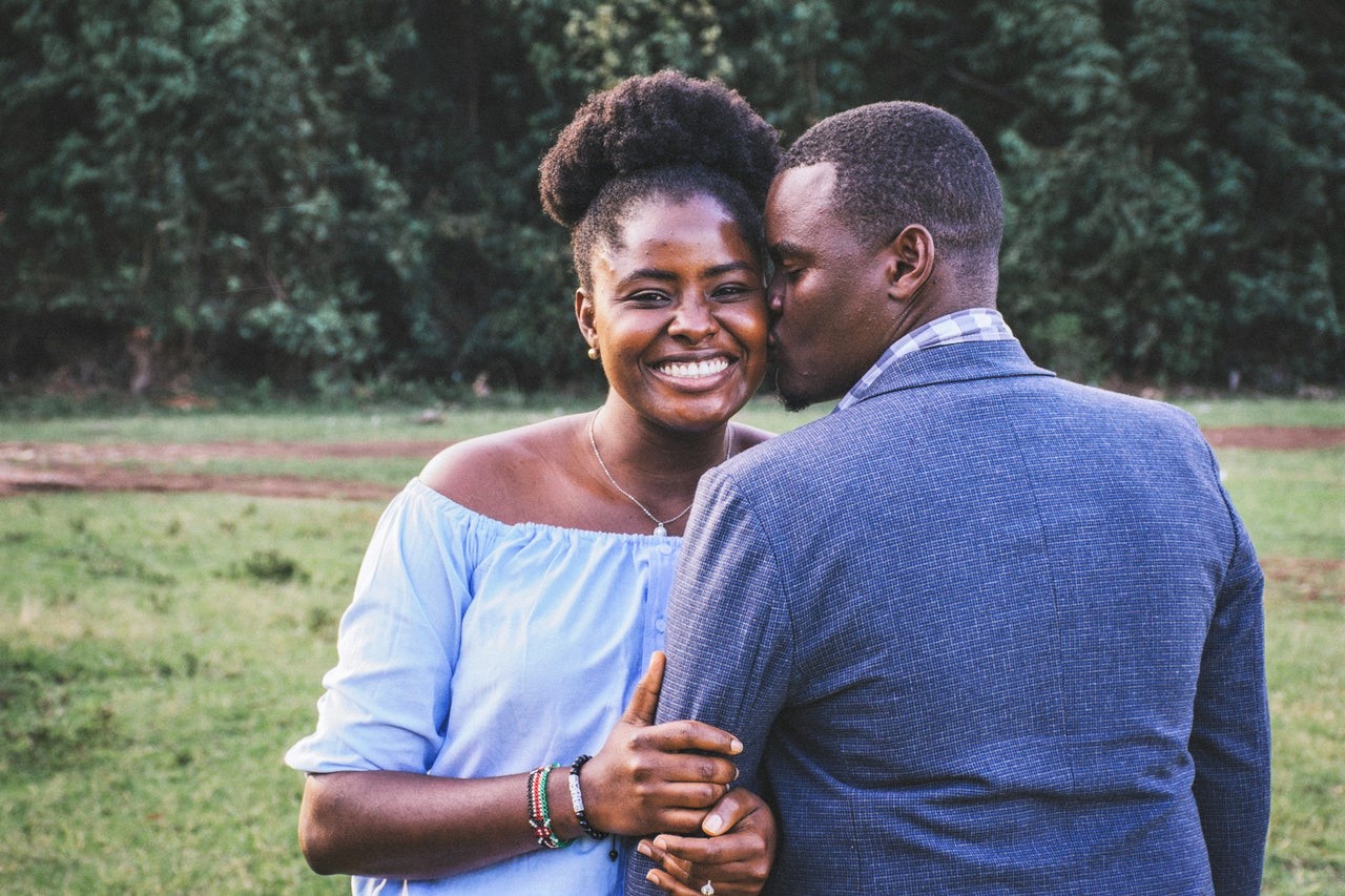 Black man kissing left cheek of black woman, expressing one of her love languages.