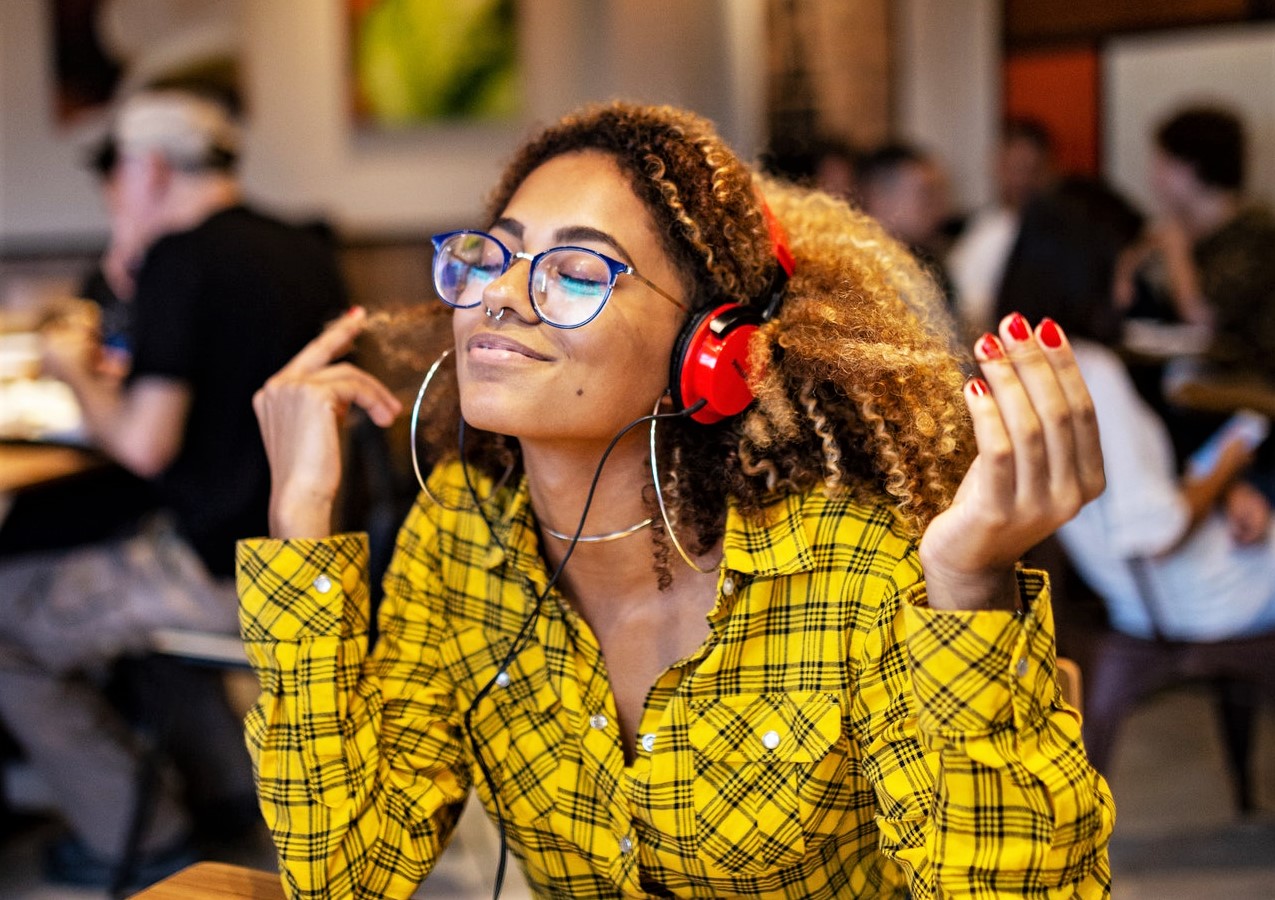 Black woman with blonde afro hair experiencing joy while listening to music.