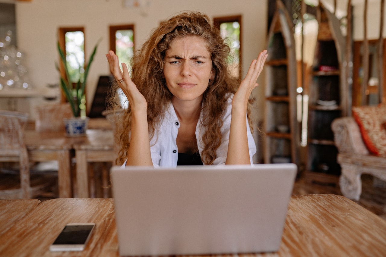 Young White woman staring frustratingly at laptop about her lack of time management.